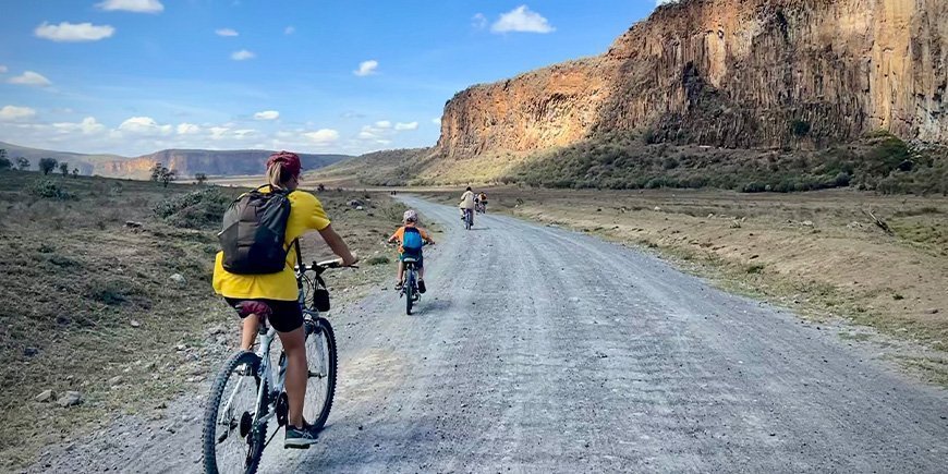 Woman and family cycling in Hells Gate National Park in Kenya.